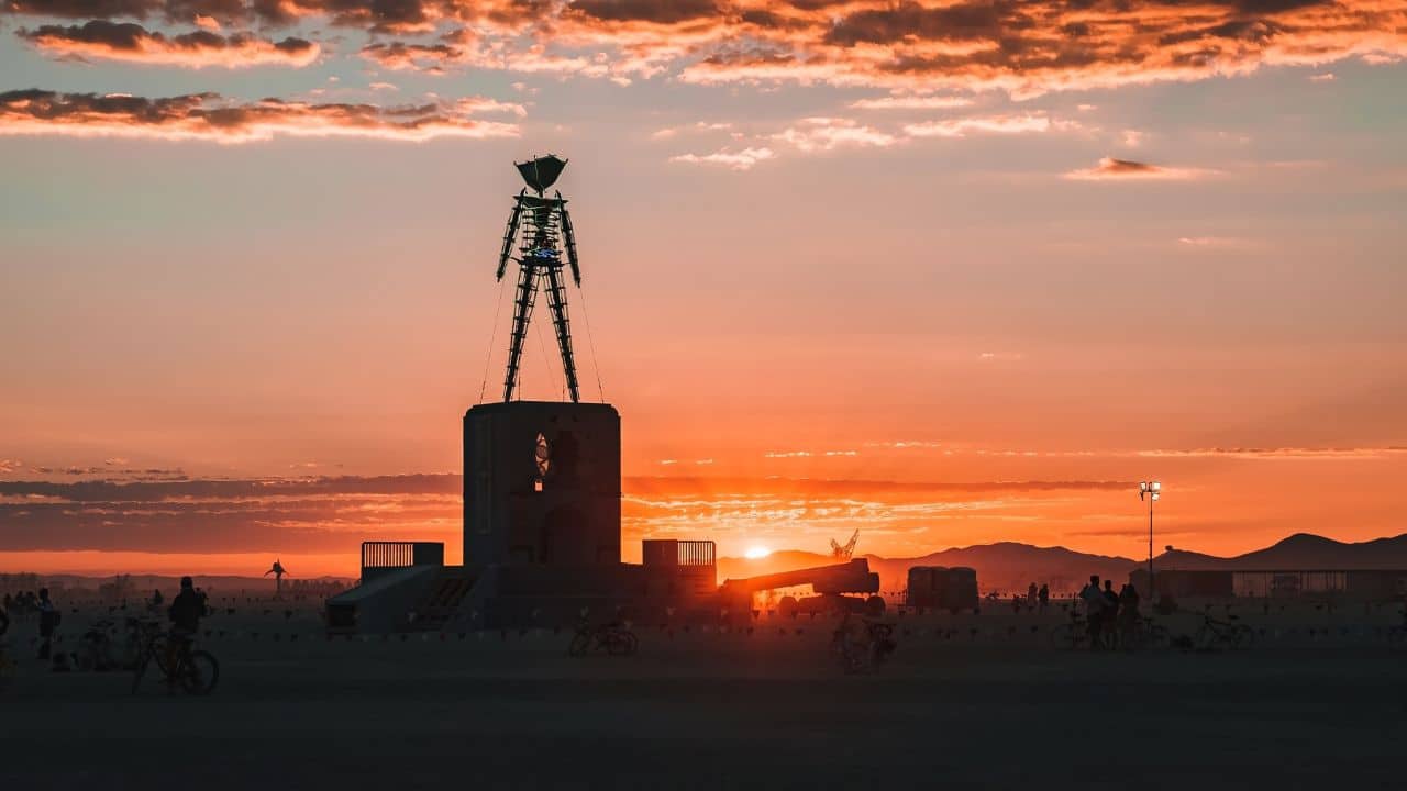 Beautiful desert with art objects at sunrise. Beautiful nature festival with people riding bicycles. Burning Man festival.