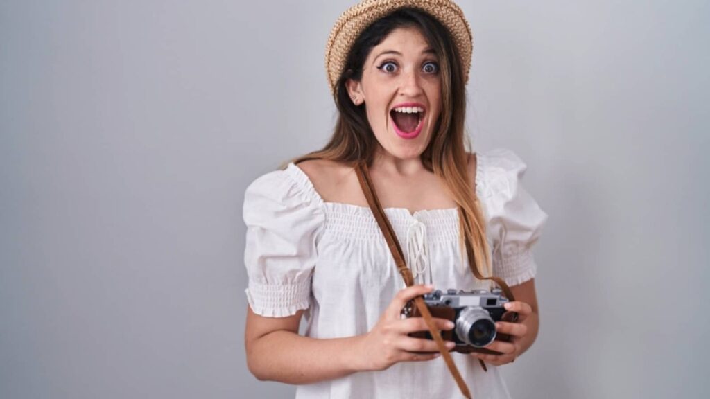 Young beautiful tourist with camera excited