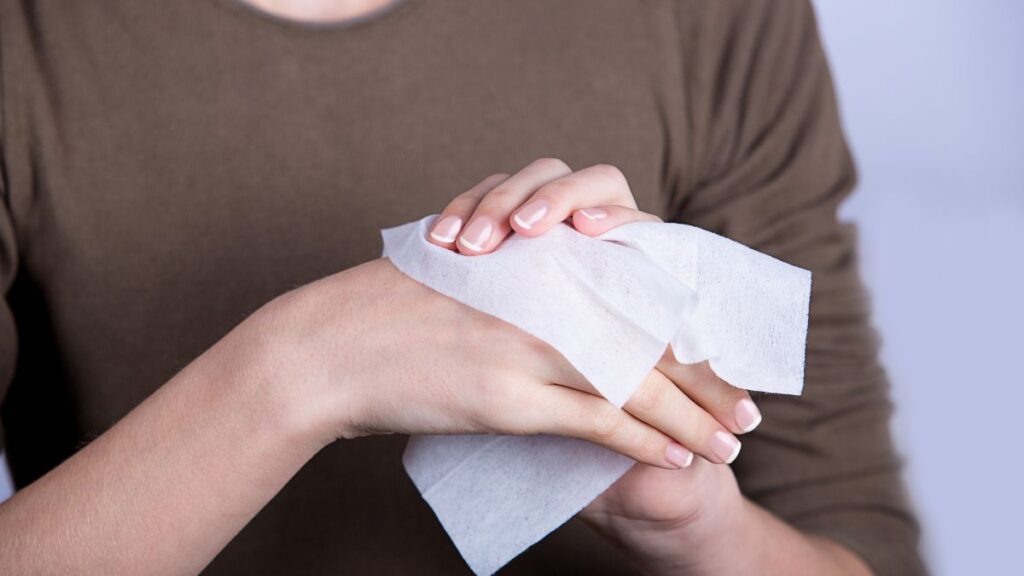 Child Hygiene.Little girl cleaning her hands with a wet baby wipe isolated on a white background.