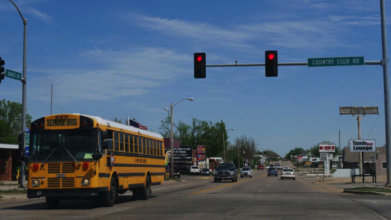 EL RENO, OKLAHOMA—SEPTEMBER 2017: A public school bus stops on a red light at the corner of Country Club Road and Sunset Drive in El Reno, Oklahoma.