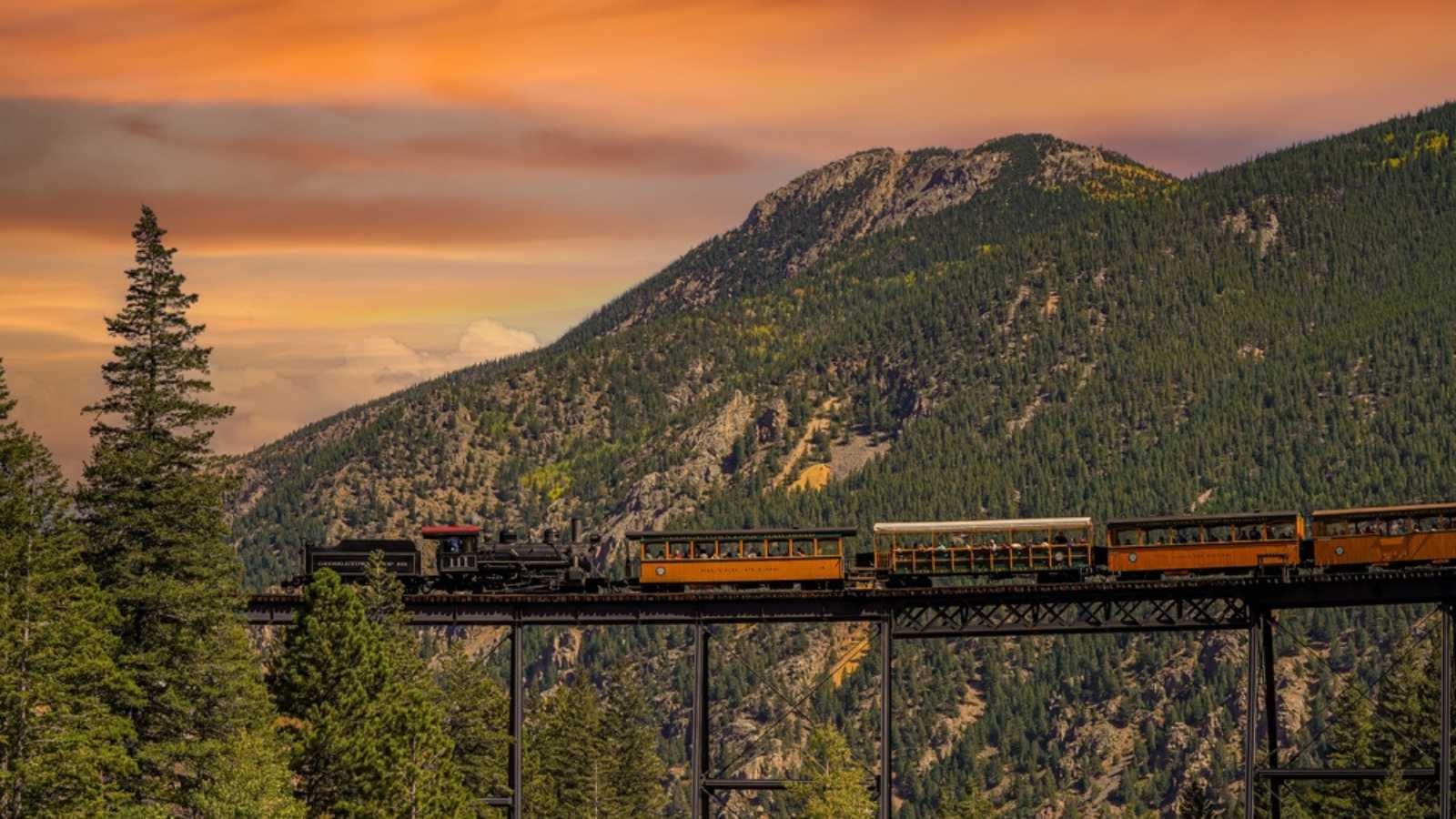 Georgetown, CO - 9-18-2021: A vintage steam locomotive with tourist passenger cars on a high bridge on the Georgetown Loop Railroad in Georgetown Colorado