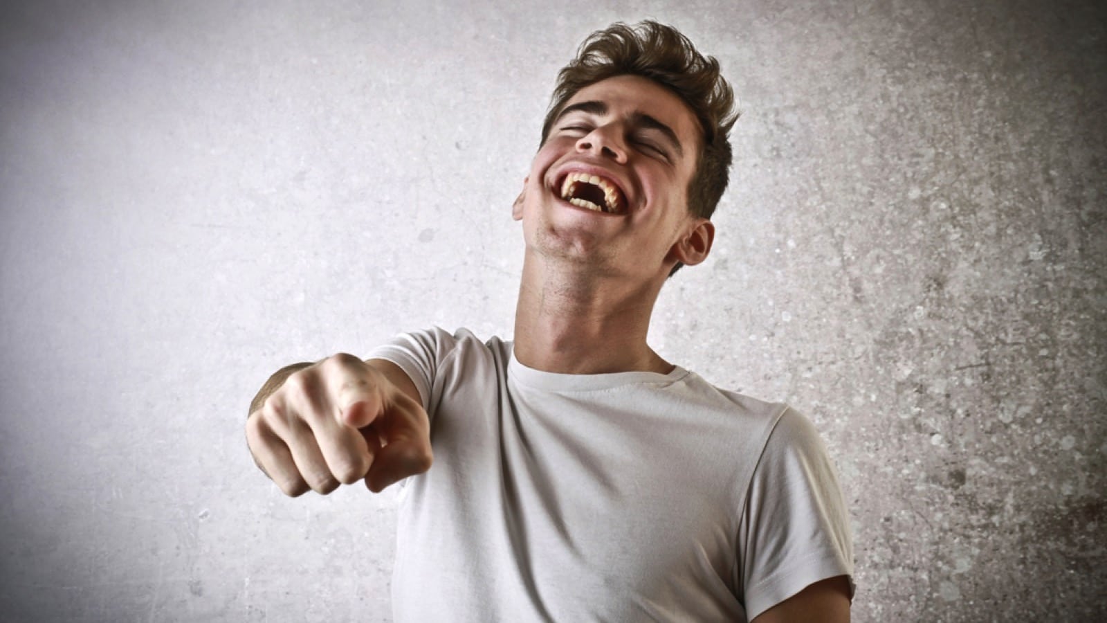 Laughing young guy pointing others