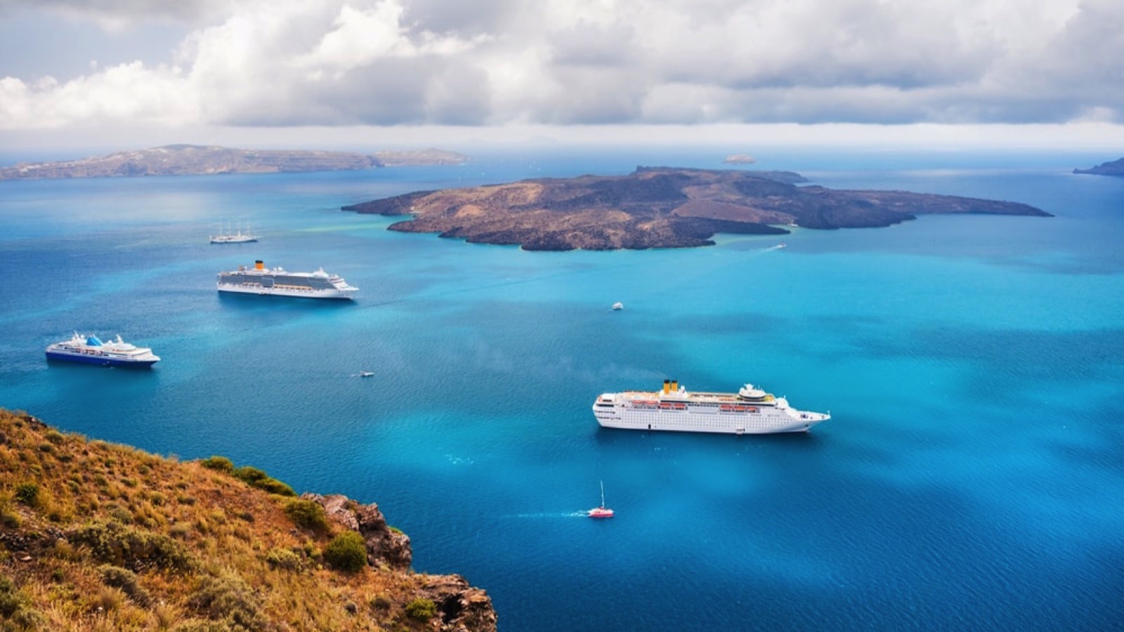 Gay Cruises: photo of cruise ships just offshore between land and an island just beyond the ships