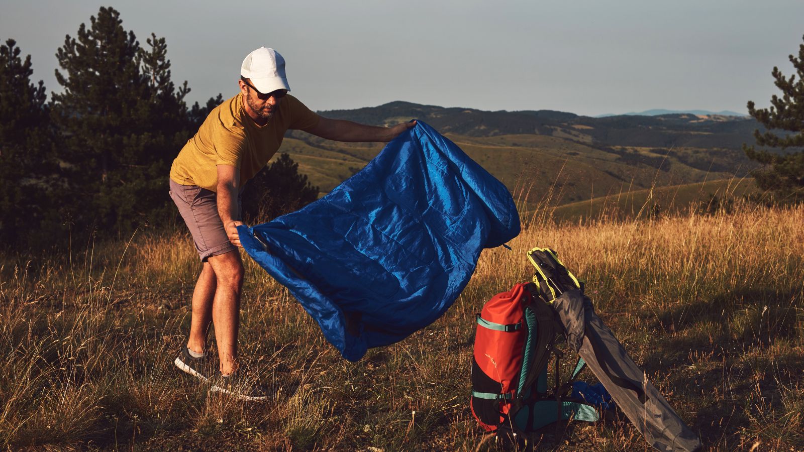 Man camping in nature, unpacking and packing small tent outdoors, recreation and hobbies.