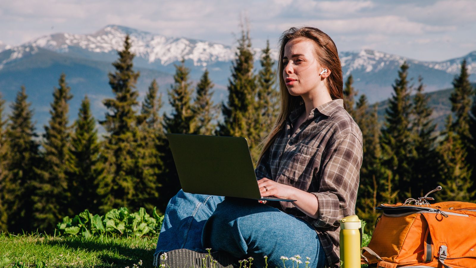 A young traveler working on a laptop in the mountains