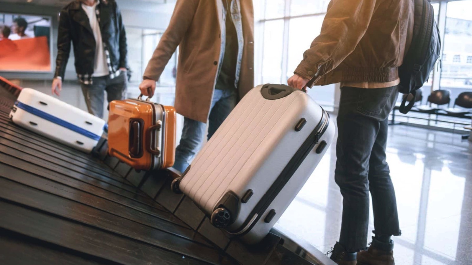 Low-angle-male-friends-putting-luggages-while-standing-in-airport