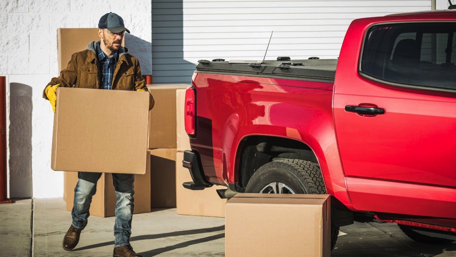 Professional-Middle-Aged-Moving-Company-Worker-Carrying-a-Cardboard-Box-with-Clients-Belongings-to-His-Big-Red-Pickup-Truck