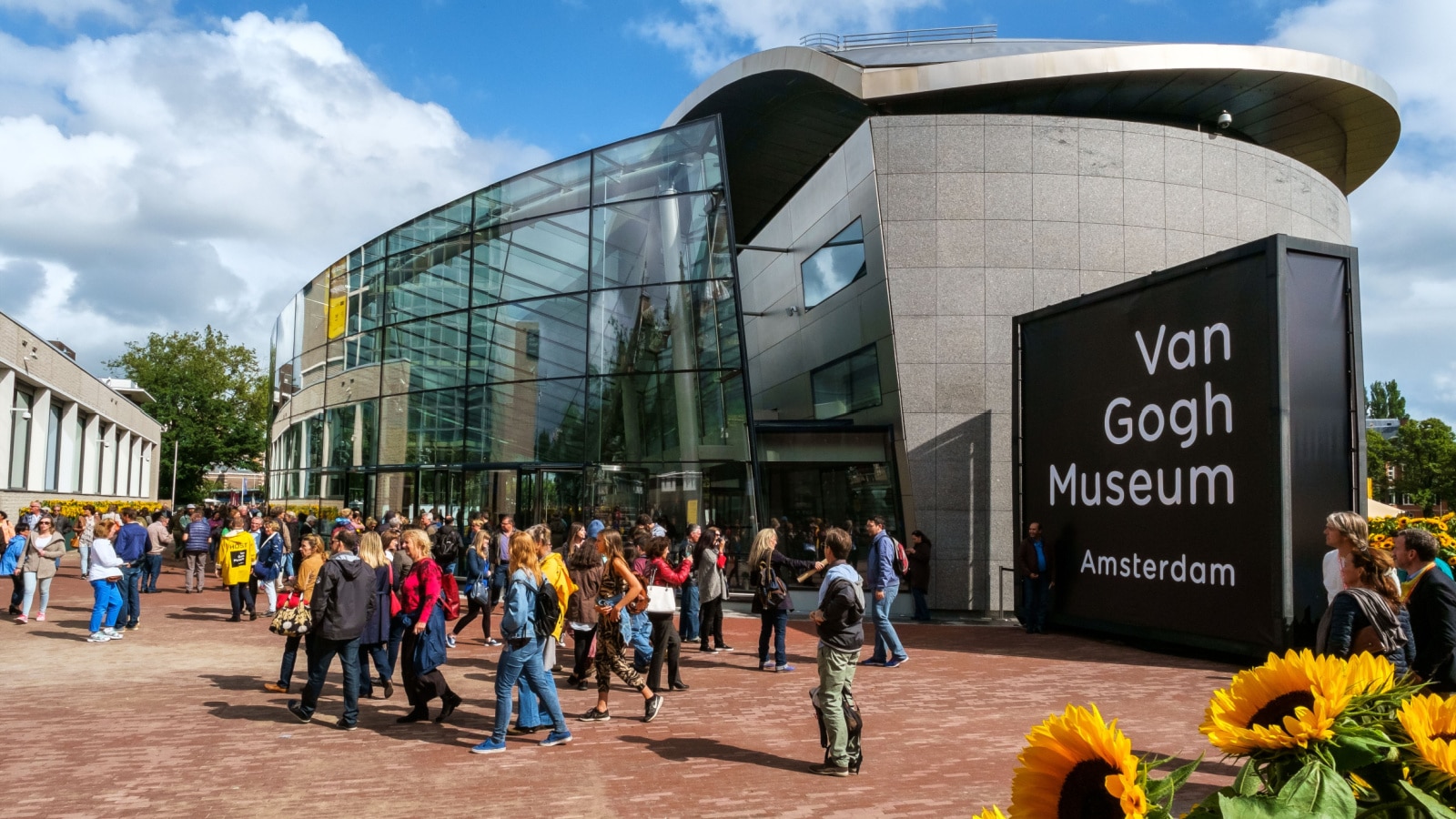 Amsterdam, the Netherlands, September 5, 2015: crowd in front of the new wing of the Van Gogh Museum with sunflowers in the foreground