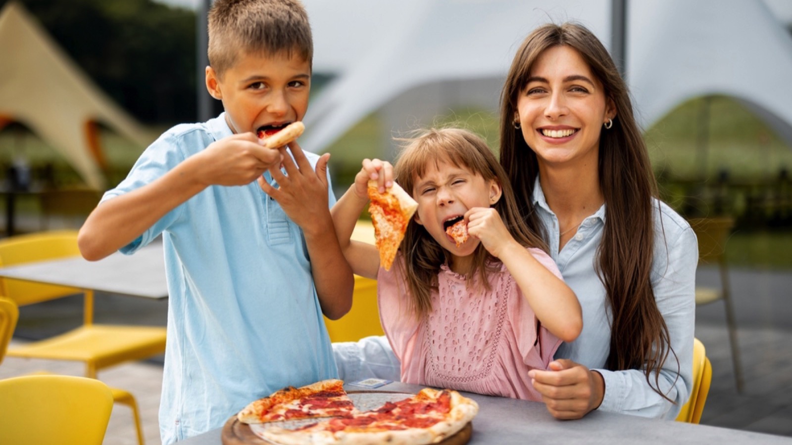 Woman with kids eating pizza in amusement park