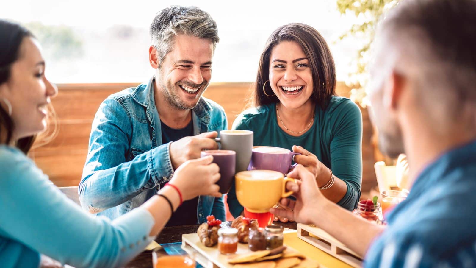 People group toasting latte at coffee bar rooftop - Friends talking and having fun together at cappuccino restaurant - Life style concept with happy men and women at cafe terrace