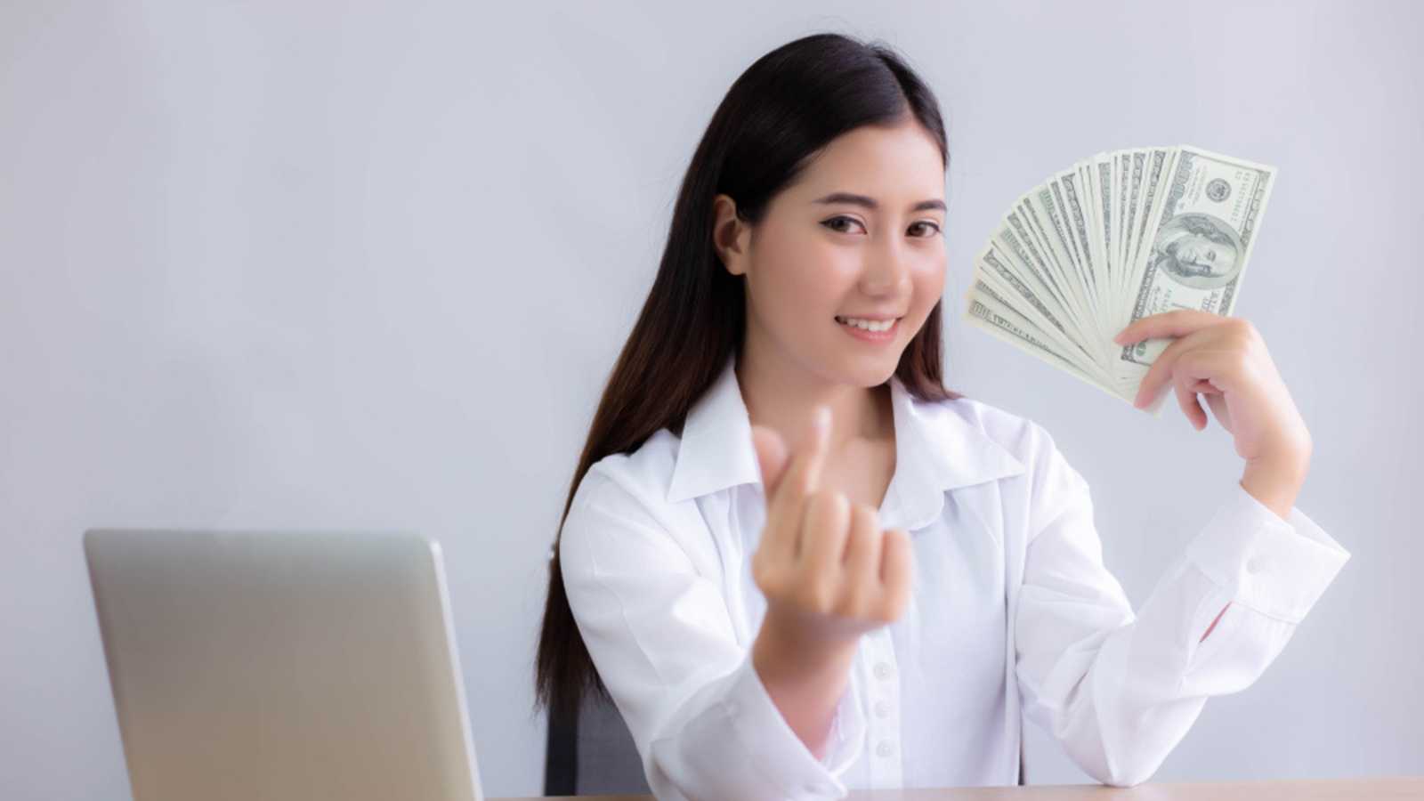 Beautiful young business woman is showing money