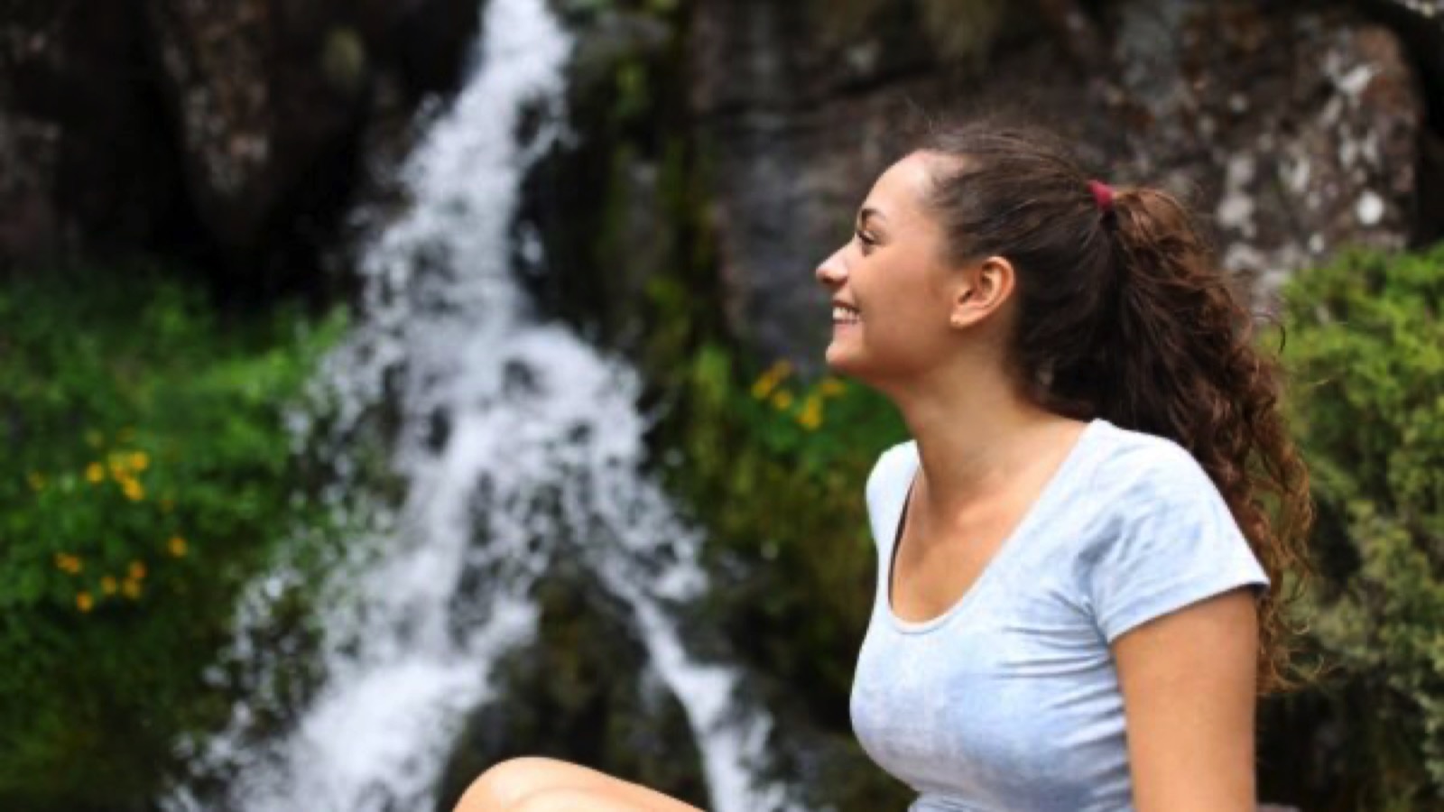 Happy woman contemplating in a waterfall