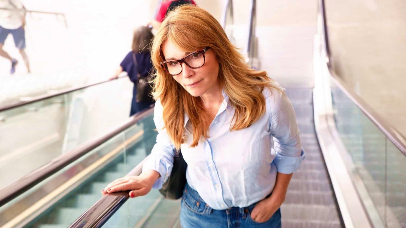 Shot-of-middle-aged-woman-smiling-while-going-up-escalator