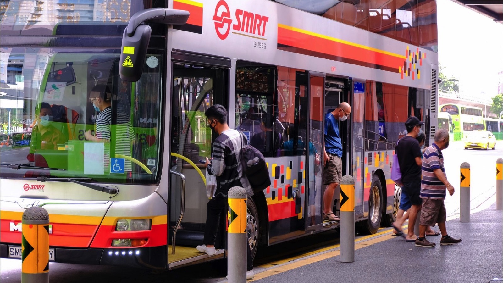 Passengers (wearing face masks) boarding, and alighting from a bus in orderly manner. 