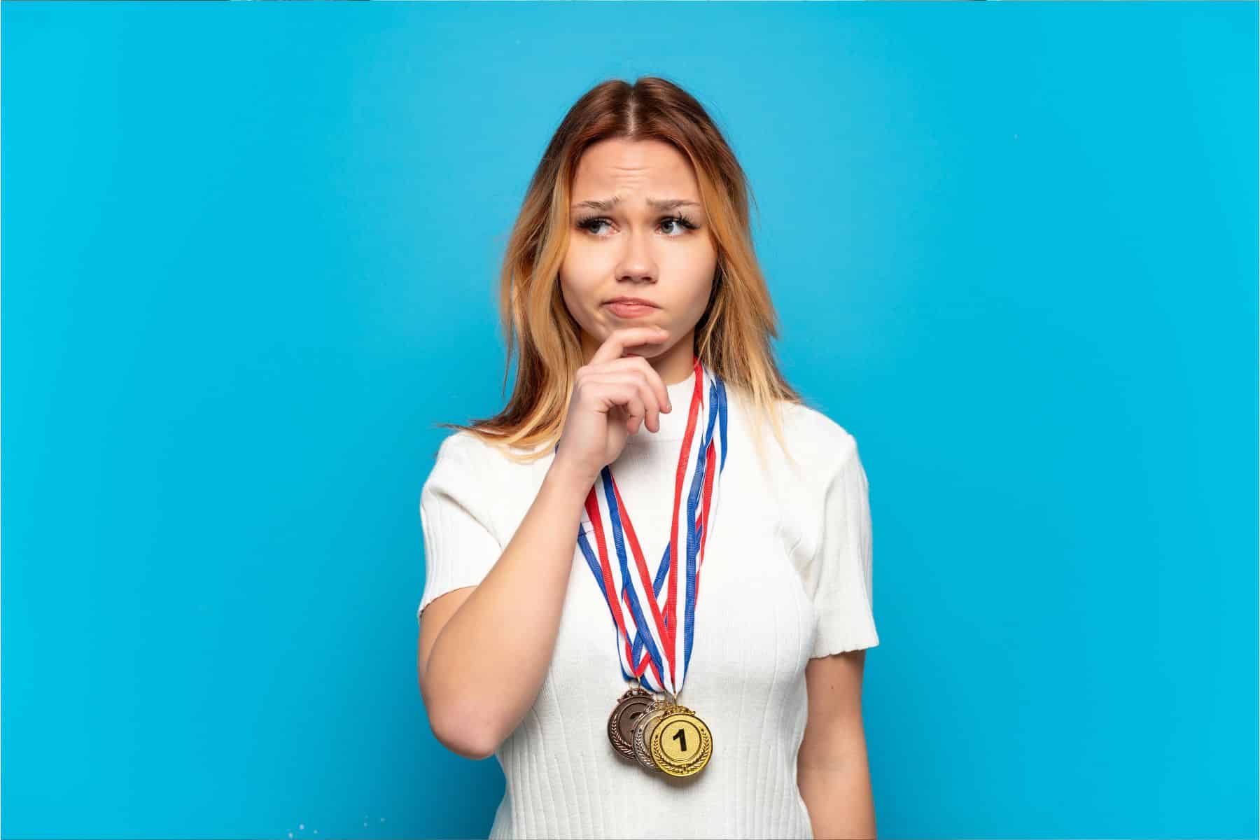 Teenager-girl-with-medals-over-isolated-background-having-doubts-and-thinking