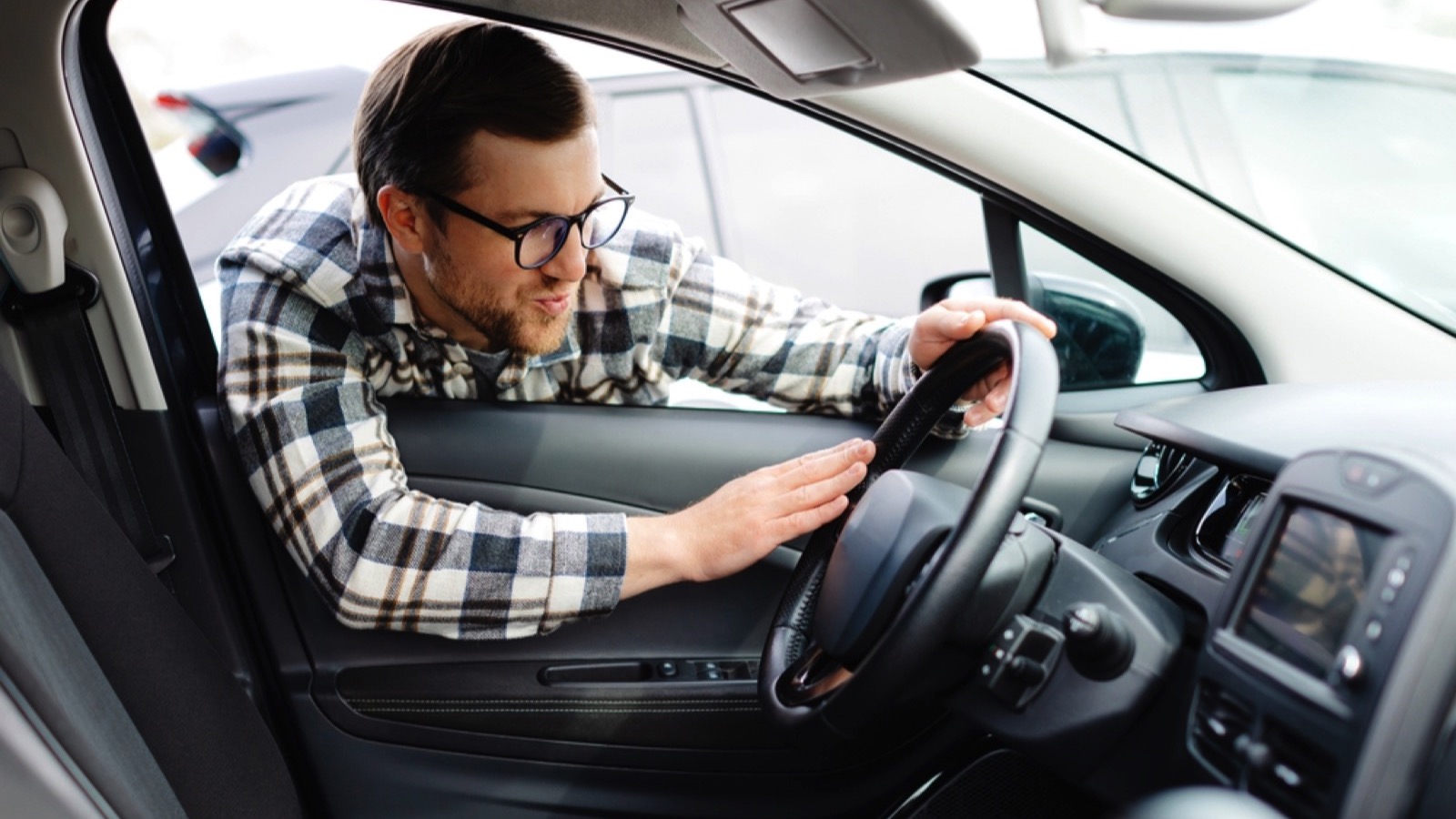 Young man looking through car window