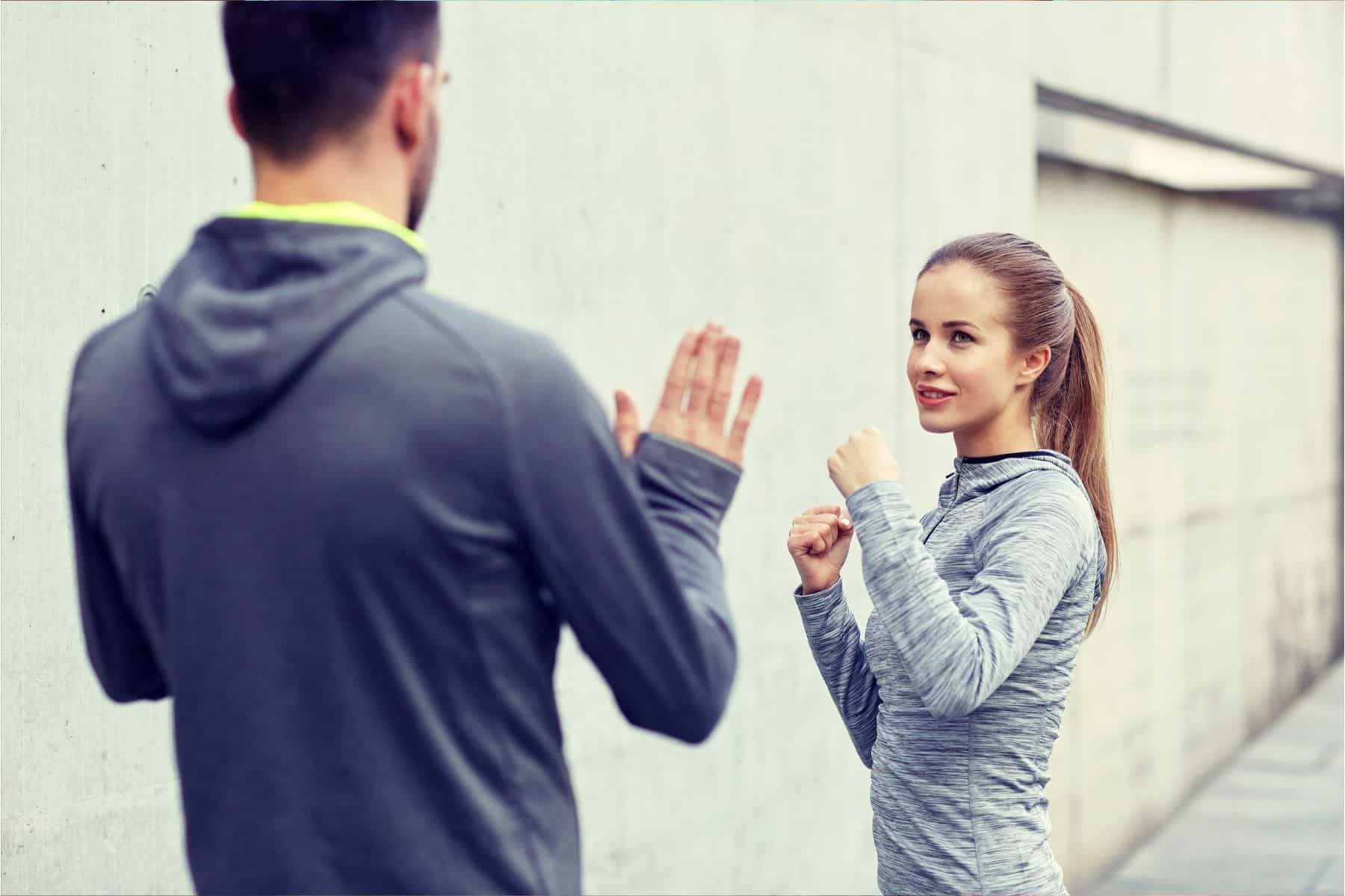 happy-woman-with-personal-trainer-working-out-strike-outdoors