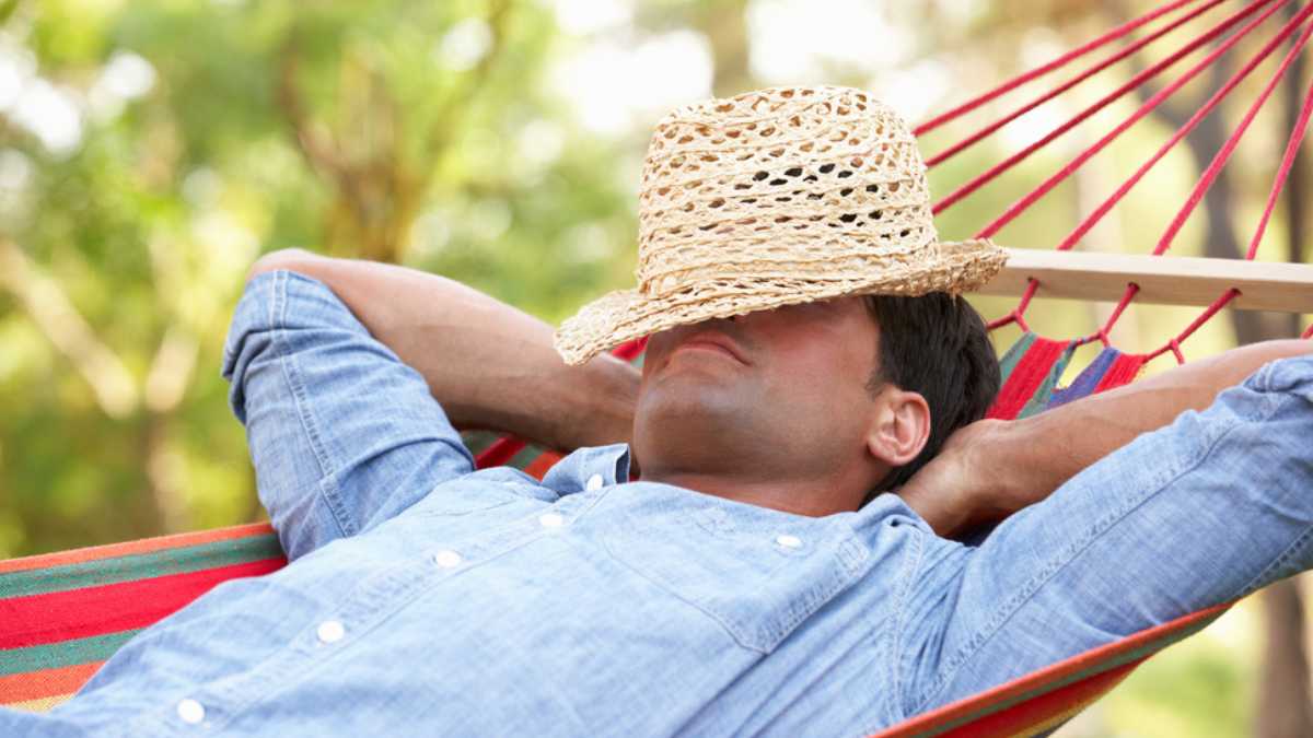 Man Relaxing In Hammock is learning how to sleep better on vacation