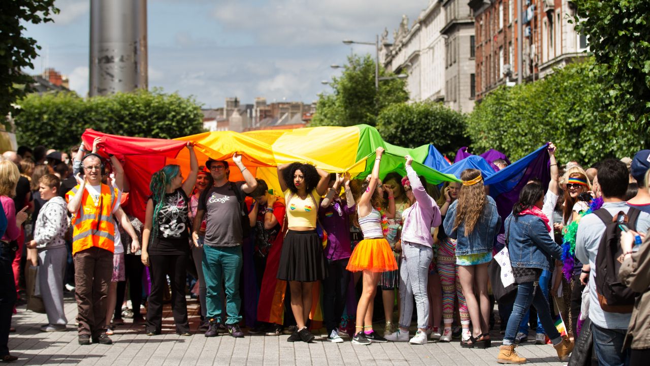 Group of gay people holding LGBTQ flag