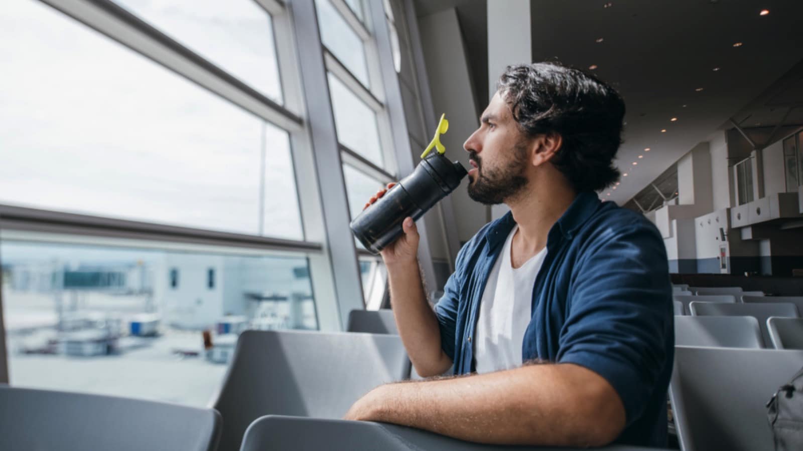 Man-siting-in-airport-drinking-water