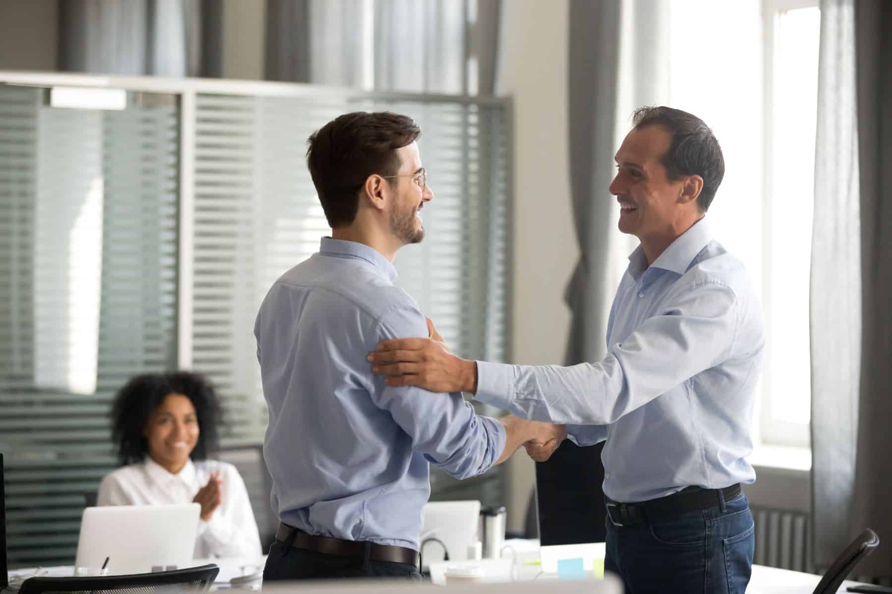 Smiling middle aged ceo promoting motivating worker shaking hands congratulating with achievement