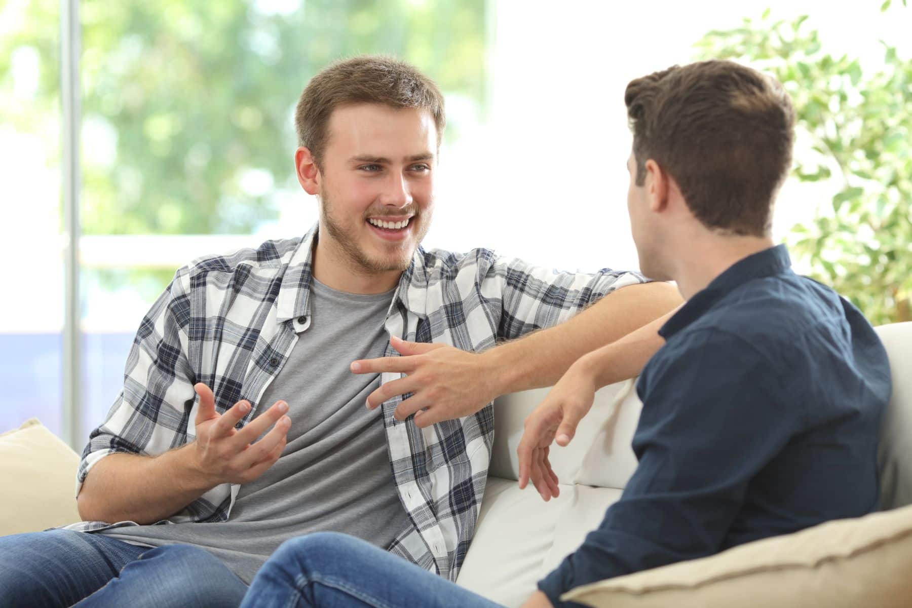 Two-friends-talking-sitting-in-a-couch-in-the-living-room