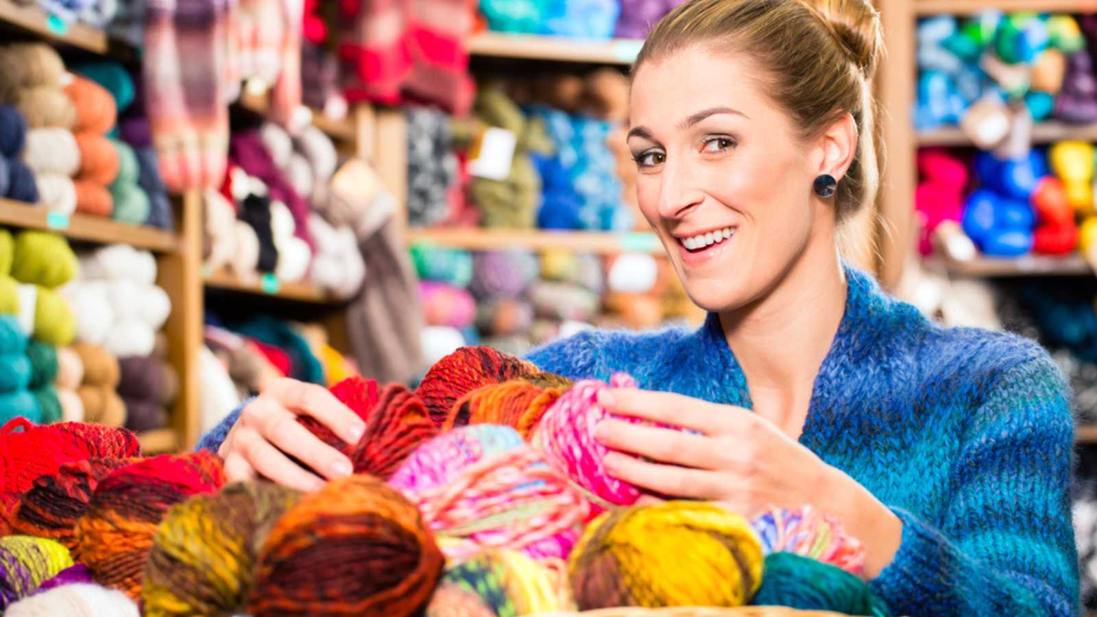 Young woman buying colorful wool and yarn for their hobby in a knitting shop