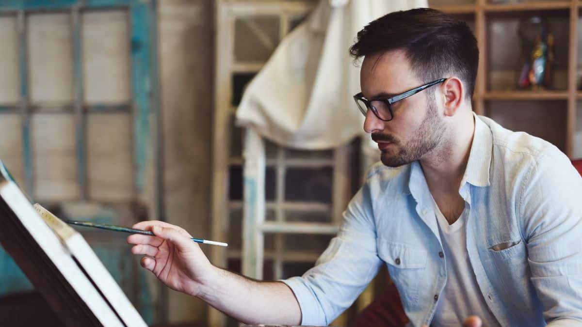 Portrait Of Male Artist Working On Painting In Studio