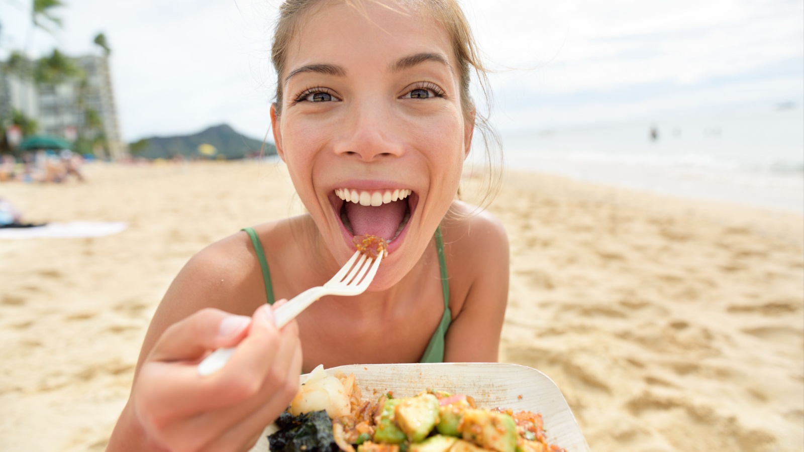 woman eating Hawaiian food on beach