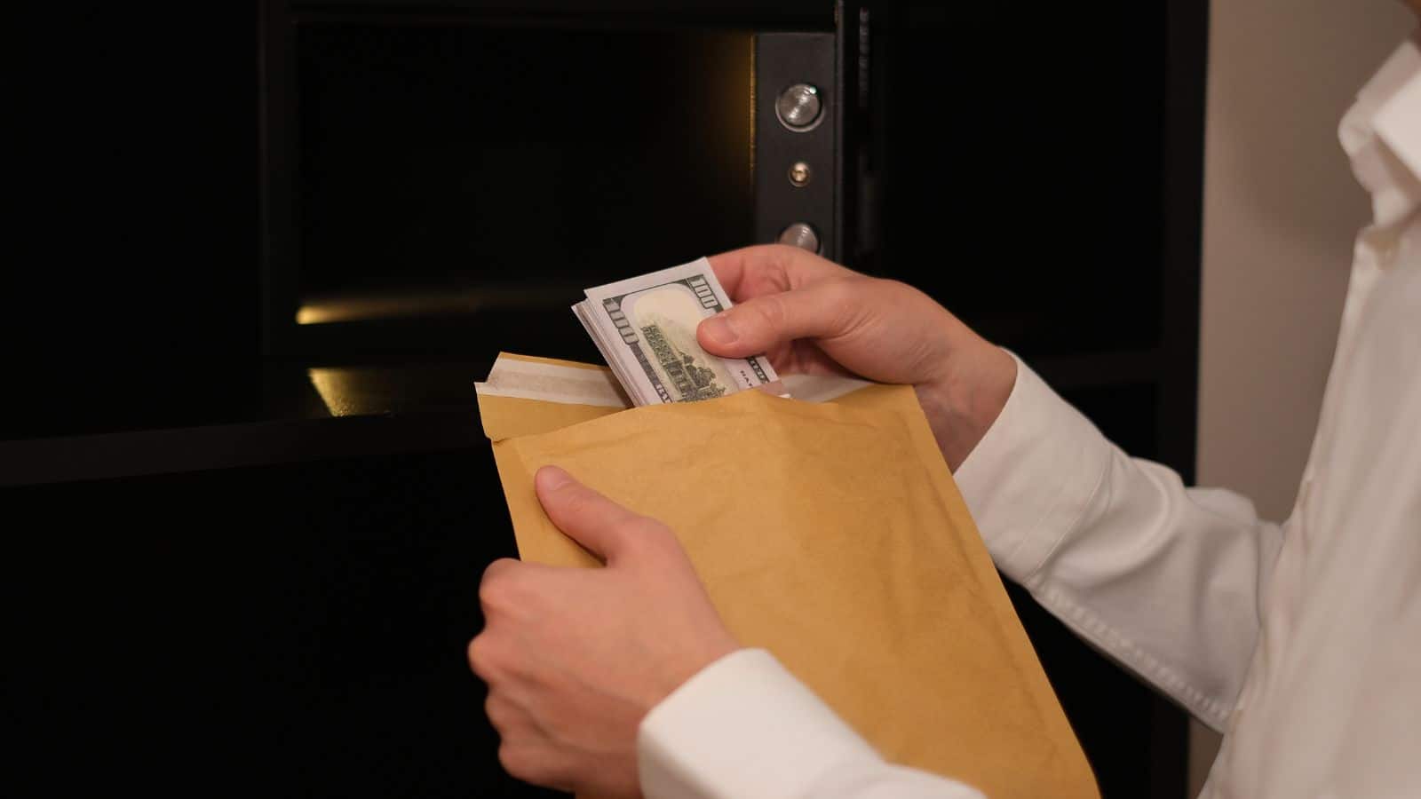 a-man-hides-money-in-an-envelope-and-puts-it-in-a-safe